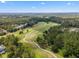 Aerial view showcases a lush golf course surrounded by mature trees and scenic landscaping at 5865 Creek Ridge Rd, Brooksville, FL 34601