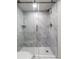 Modern shower featuring gray marble tile, a built-in shelf, and a sleek sliding glass door at 700 Beach Ne Dr # 705, St Petersburg, FL 33701