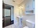 Bright bathroom with a pedestal sink, white cabinets, and neutral tile, offering a clean and classic design at 705 Cypress St, Tarpon Springs, FL 34689