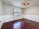 Cozy bedroom with gleaming hardwood floors, wainscoting, ceiling fan, and a bright window at 705 Cypress St, Tarpon Springs, FL 34689