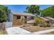 Charming home featuring a stone facade, bright red door, driveway, and tropical landscaping at 705 Cypress St, Tarpon Springs, FL 34689