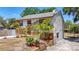 Charming home featuring a stone facade, bright red door, and mature tropical landscaping at 705 Cypress St, Tarpon Springs, FL 34689