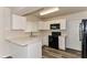 Updated kitchen features white cabinets, black appliances, and a breakfast bar at 7517 Oxwood St, North Port, FL 34287