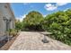 Paver patio with a small table and privacy hedges under a bright, sunny sky at 7903 Lake Placid Ln, Trinity, FL 34655