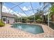Backyard view of caged pool with brick trim and lush landscaping at 7903 Lake Placid Ln, Trinity, FL 34655