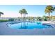 Sparkling community pool surrounded by lounge chairs and palm trees overlooking the water at 8000 Sailboat Key S Blvd # 202, St Pete Beach, FL 33707