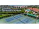 Aerial view of well-kept tennis courts with surrounding landscaping and nearby marina at 8000 Sailboat Key S Blvd # 202, St Pete Beach, FL 33707