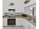 Bright kitchen with stainless steel oven, granite countertops, and white cabinets at 8124 Golf Club Ct, Hudson, FL 34667