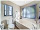 Bathroom featuring a large soaking tub with blue blinds and a toilet next to it at 8127 Tarsier Ave, New Port Richey, FL 34653