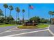 Welcoming community entrance with manicured landscaping and the American flag waving in a clear blue sky at 8211 Canyon Creek Way, Tampa, FL 33647