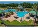 Aerial view of a pool with umbrellas, tables, lounge chairs, and beautiful landscaping at 8211 Canyon Creek Way, Tampa, FL 33647