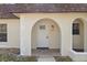 Close up of the home's arched front doorway with white trim and light fixture at 9922 86Th Way, Seminole, FL 33777