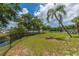 Community lawn area with mature trees and chain-link fence at 9922 86Th Way, Seminole, FL 33777