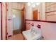 Bathroom with pink tile, classic fixtures, and an open doorway to another room at 111 Orangeview Ave, Clearwater, FL 33755