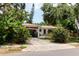 Front exterior of a single story home with an attached carport, an overgrown driveway, and mature landscaping at 111 Orangeview Ave, Clearwater, FL 33755