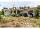 A single-story house with a white exterior and a covered carport, surrounded by overgrown landscaping at 111 Orangeview Ave, Clearwater, FL 33755