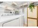 A functional laundry room with white appliances, storage shelves, and an organized space at 1281 Pine Ridge E Cir # H1, Tarpon Springs, FL 34688