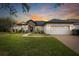 Charming home with a manicured lawn, stone accents, and a brick driveway at sunset at 14019 Nighthawk Ter, Lakewood Ranch, FL 34202