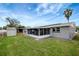 A spacious backyard featuring a screened-in porch, storage shed, palm tree, and lush green lawn at 1516 Roundtree Rd, Holiday, FL 34690