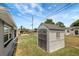 Backyard view of a well-maintained shed with neutral tones and double doors in a fenced yard at 1516 Roundtree Rd, Holiday, FL 34690