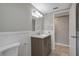 Well-lit bathroom with a modern vanity, decorative mirror, and white wainscoting at 1516 Roundtree Rd, Holiday, FL 34690