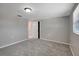 Spacious bedroom features neutral gray walls and plush carpeting, illuminated by a ceiling light and natural light at 1516 Roundtree Rd, Holiday, FL 34690