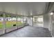 View of the enclosed patio with grey floor and frame windows and a sliding glass door to the home at 1516 Roundtree Rd, Holiday, FL 34690