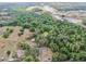 Property aerial view surrounded by green trees with a small pond nearby, distant houses in the background at 1641 Thompson Rd, Lithia, FL 33547