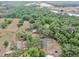 Aerial view of a home nestled among mature trees, with a pond and a neighboring community in the distance at 1641 Thompson Rd, Lithia, FL 33547