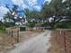 Long driveway leading to a single-story home and a detached garage, all set amidst a landscape with mature trees at 1641 Thompson Rd, Lithia, FL 33547
