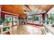 Cozy sunroom features brick fireplace, wood ceiling, hardwood floors, and large windows with views of the backyard at 1641 Thompson Rd, Lithia, FL 33547