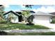 Charming blue home with manicured lawn, mature trees, and attached two-car garage at 16505 Lake Heather Dr, Tampa, FL 33618