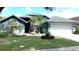 Charming blue home with manicured lawn, mature trees, and attached two-car garage at 16505 Lake Heather Dr, Tampa, FL 33618