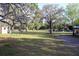 Large grassy front yard with scattered trees, outbuildings, and ample space for outdoor activities at 16536 Caldwell Ln, Spring Hill, FL 34610
