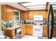 Well-lit kitchen with warm wood cabinets, white appliances, and functional layout for efficient cooking at 16536 Caldwell Ln, Spring Hill, FL 34610