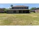 Expansive backyard with a lawn and a two-story home featuring a covered patio and multiple windows at 16637 Ashton Green Dr, Lutz, FL 33558