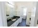 Bathroom features a vanity with black countertops, a large mirror, and tile flooring at 16637 Ashton Green Dr, Lutz, FL 33558
