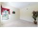 Bright bedroom with neutral carpet, window with red curtains, and a decorative plant at 16637 Ashton Green Dr, Lutz, FL 33558