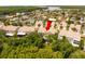An aerial view of a tan two story home with a tile roof and lush green trees surrounding the property at 1750 Arabian Ln, Palm Harbor, FL 34685