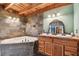 Rustic bathroom featuring a soaking tub with slate surround and a wooden double vanity with a decorative mirror at 19708 Bower Rd, Dade City, FL 33523
