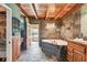 A bathroom with stone walls, wood floors and a tub at 19708 Bower Rd, Dade City, FL 33523
