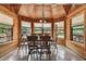 Cozy dining room with wood-paneled walls and ceiling, surrounded by windows that offer scenic views, creating a warm ambiance at 19708 Bower Rd, Dade City, FL 33523