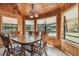 Inviting dining room with wood-paneled walls, multiple windows, and a rustic chandelier, providing ample natural light at 19708 Bower Rd, Dade City, FL 33523
