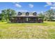 Inviting log cabin with a wide, covered front porch, perfect for enjoying the tranquil, expansive lawn and outdoor scenery at 19708 Bower Rd, Dade City, FL 33523