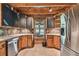 Functional kitchen layout featuring stainless steel appliances, rustic cabinets, and tile backsplash with granite countertop at 19708 Bower Rd, Dade City, FL 33523