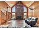 Spacious living room featuring a wood-burning fireplace, wood walls, and large windows at 19708 Bower Rd, Dade City, FL 33523