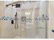Modern shower featuring decorative blue tile accent, rainfall shower head, and glass door at 19708 Bower Rd, Dade City, FL 33523