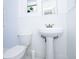 Bright bathroom features a pedestal sink, toilet, and a small window providing natural light at 211 80Th N Ave, St Petersburg, FL 33702