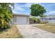 Exterior shot of home showing the garage and driveway, accented by palm trees and surrounding greenery at 211 80Th N Ave, St Petersburg, FL 33702