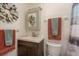 Bathroom with wood-look vanity, decorative mirror, decorative wreath, and brown and gray towels at 2153 Pocahontas Dr, Largo, FL 33774